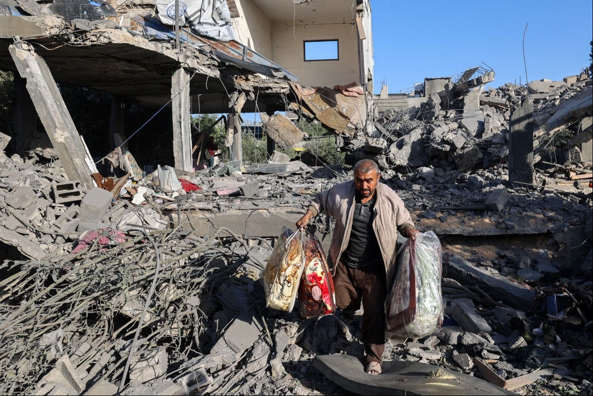 Palestino carrega objetos após sua residência ser destruída em bombardeio