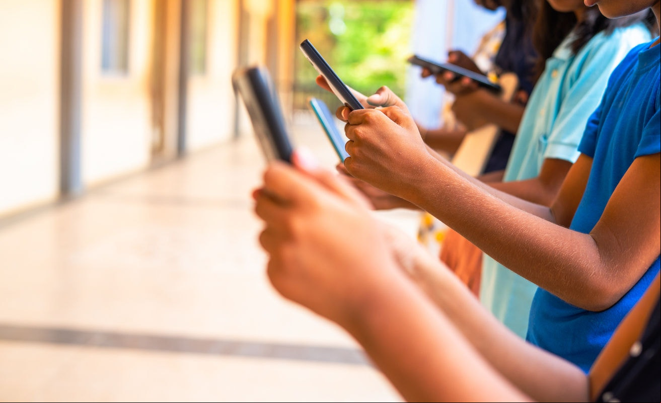 Close up shot, group of children hands busy using smartphone at school corridor - concept of social media, playing games, technology and education.
