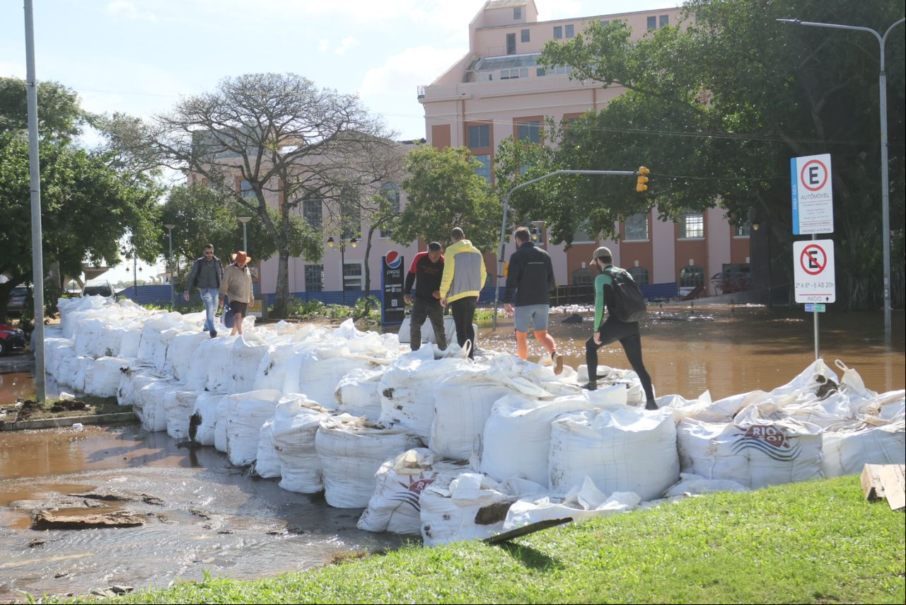 Pedestres am por cima de sacos de areia na região do Cais do Porto, em Porto Alegre